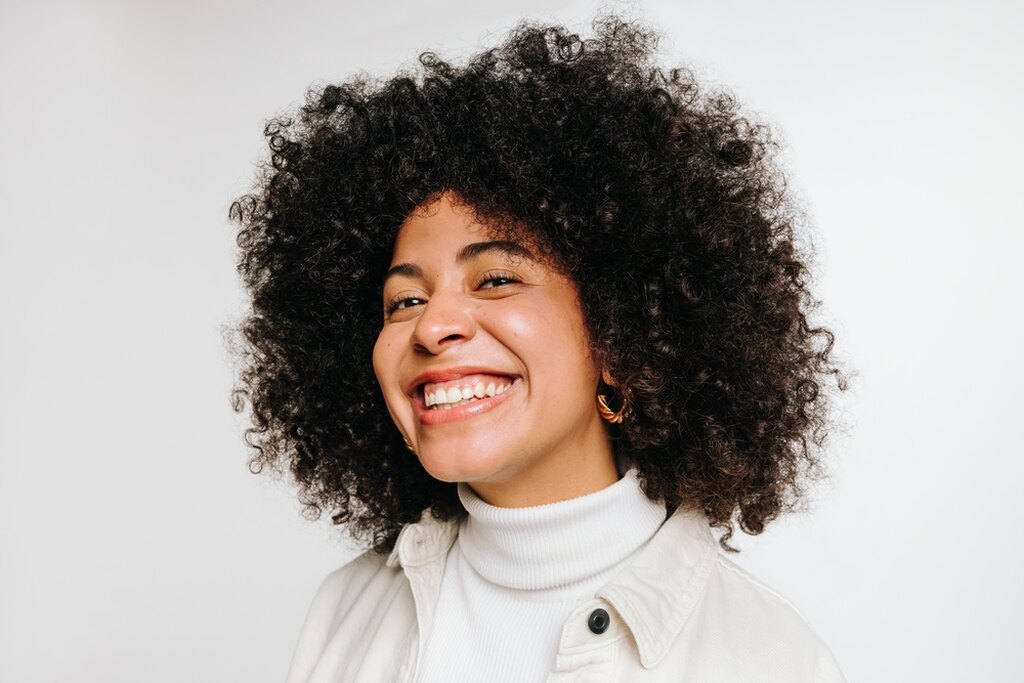 Nariz negróide, mulher negra feliz e sorridente olhando para a câmera